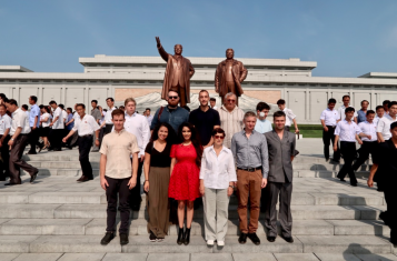 A group of tourists pose in front of the Mansudae statues of Kim Il Sung and Kim Jong Il.