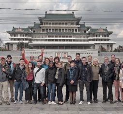 A group of smiling tourists pose in front of Grand People's Study House in Pyongyang.