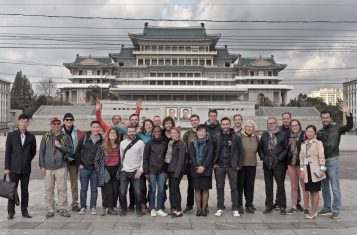 A group of smiling tourists pose in front of Grand People's Study House in Pyongyang.