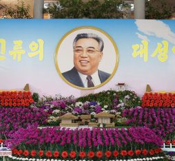A large picture of Kim Il Sung surrounded by kimilsungia and kimjongilia flowers.