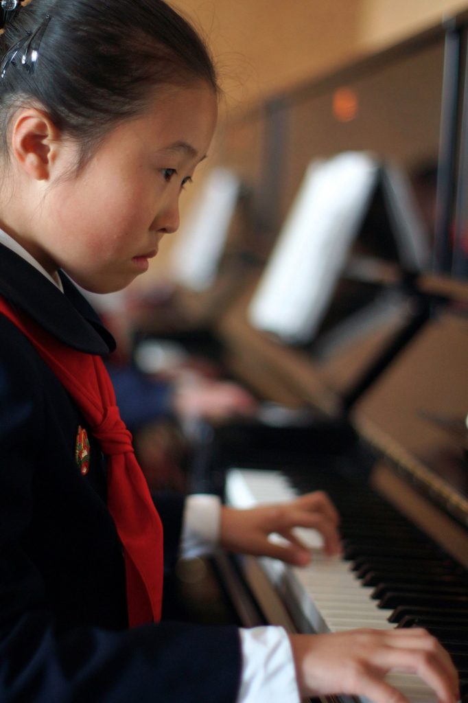 A girl playing piano during her afterschool classes in Mangyongdae