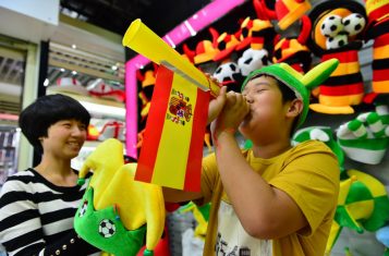 Child blowing horn with spanish flag hanging off the horn