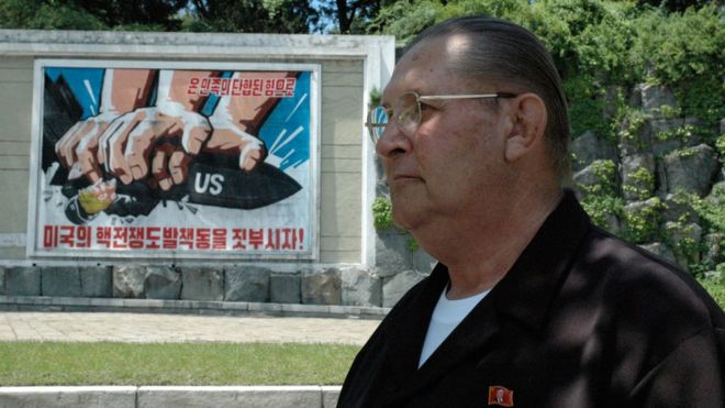 James Dresnok, an infamous North Korean celebrity, poses in front of an anti-US propaganda poster. 