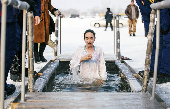 Festivals in Transnistria: a young woman wearing a transparent white robe and bikini plunges into freezing waters during the Orthodox Epiphany festival in Transnistria.