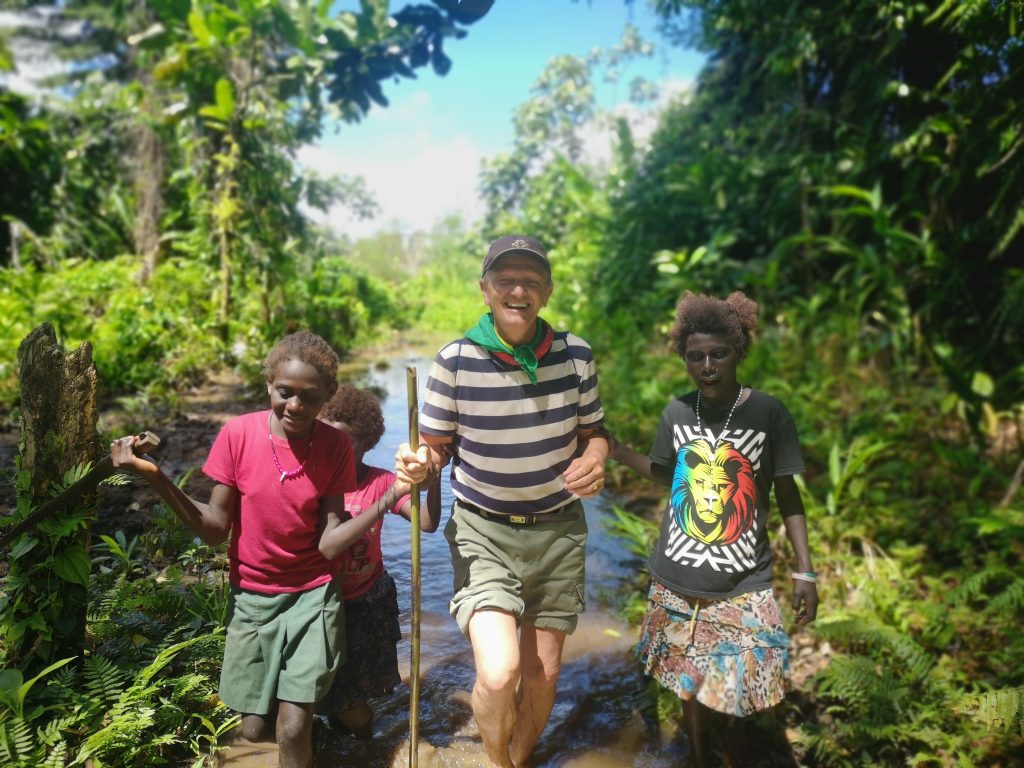 Locals assist a pioneer as he walks on the trek path to the wreck of Admiral Yamamoto's aircraft