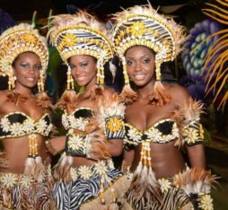Three women in flamboyant costumes pose at the Angola Carnival.