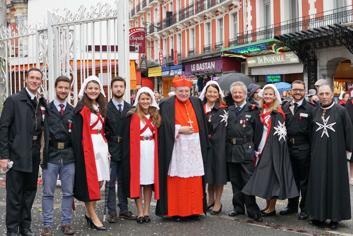 Dames and Knights of the Sovereign Military Order of Malta pose for a photo in the street. 