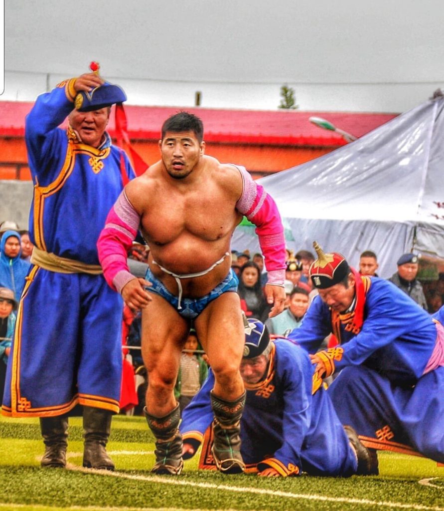 Mongolian people: a muscular Mongolian wrestler strides towards the starting point for his bout. 