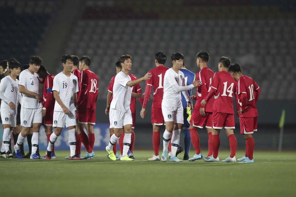 The national squads of North and South Korea greet other before playing their qualifier in an empty Pyongyang stadium. 