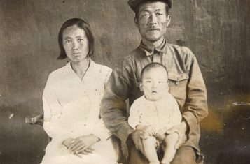 An ethnic Korean father and mother with their infant child pose in this sepia picture.