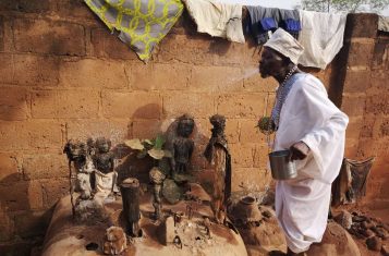 A voodoo priest making offerings to voodoo idols in Abomey