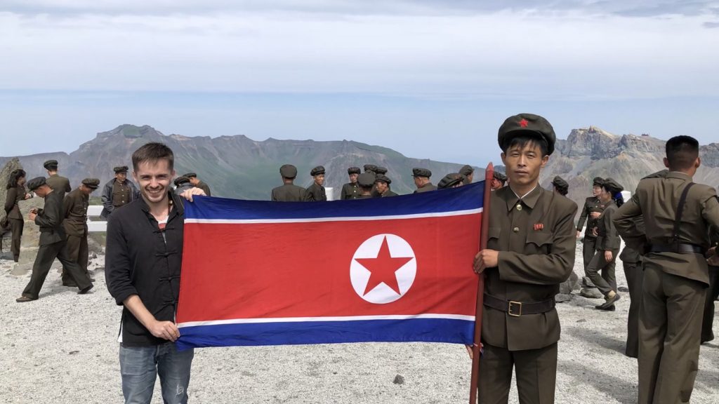 Simon holding the flag of the DPRK on Mt Paektu during his Pyongyang Korean Language Study Tour